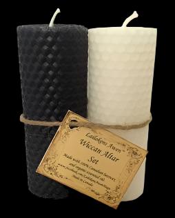 Two textured pillar candles, one dark charcoal gray and one off-white, tied together with twine and a paper tag that reads 'Lauchlin's Aves Wickam Allur Salt'.