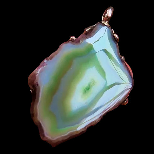 Agate pendant held in a hand with a wooden background
