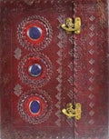 Decorative red leather-bound book with gold clasps and blue stones